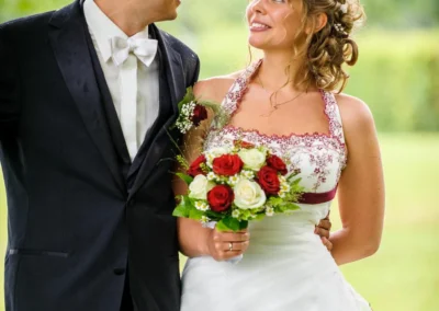 Brautpaar laechelt sich an, Brauttraeger mit Blumenstrauss in der Gemeinde Kochel am See bei Hochzeitsfotografie.