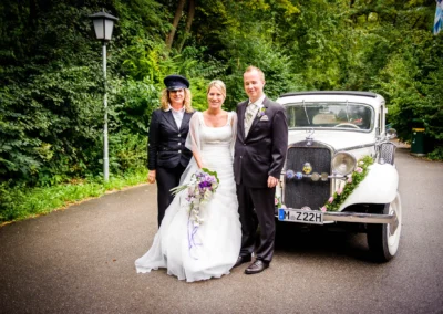 Brautpaar mit Chauffeur vor Oldtimer im Englischen Garten, Hochzeitsreportage in Muenchen.