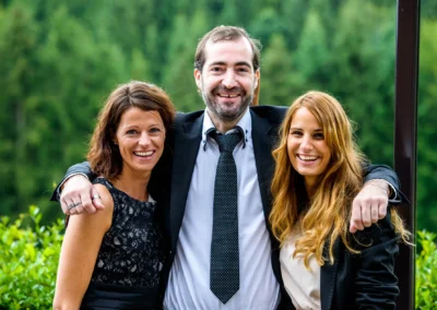 Personen lachen gemeinsam bei einer Hochzeit nahe Tegernsee, umgeben von gruenem Waldhintergrund. Hochzeitsreportage.
