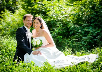 Brautpaar lacht in einem gruenerfeld bei ihrer Hochzeitsfotografie in Eurasburg bei Wolfratshausen.
