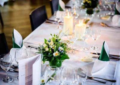 Elegante Hochzeitstafel im Kloster Seeon, dekoriert mit Kerzen und Blumengesteck, aufgenommen von Hochzeitsfotograf.