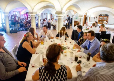 Gäste sitzen bei Hochzeitsfeier im Landgasthof Stahuber Thal. Hochzeitsreportage mit Band im Hintergrund.