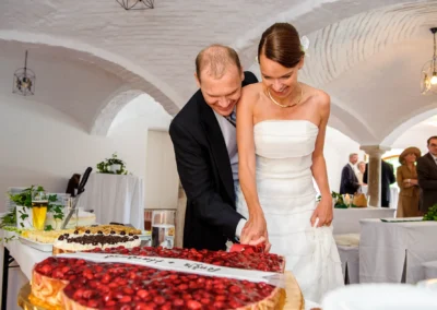 Brautpaar schneidet Hochzeitstorte bei Hochzeit auf Gut Thurnsberg, Hochzeitsreportage in Oberbayern.