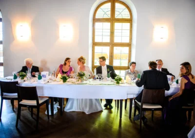 Hochzeitsgesellschaft am Tisch im Kloster Seeon. Hochzeit im Chiemgau mit Brautpaar und Gaesten.
