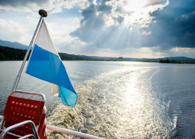 Flagge weht auf einem Boot auf dem Staffelsee bei einer Hochzeit, unter dramatischem Himmel. Hochzeitsfotografen-Aufnahme.