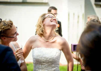 Braut lacht glücklich bei Hochzeitsfeier in Schwabing, umgeben von Freunden. Hochzeitsfotografie für emotionale Momente.