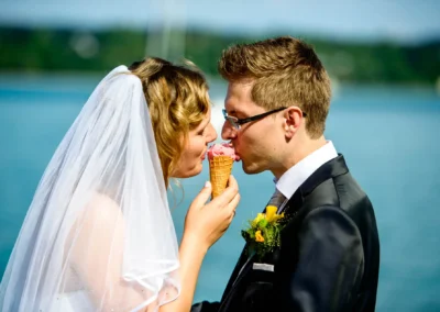 Brautpaar teilt Eis an ihrer Hochzeit am Starnberger See. Romantische Hochzeitsfotografie unter freiem Himmel.