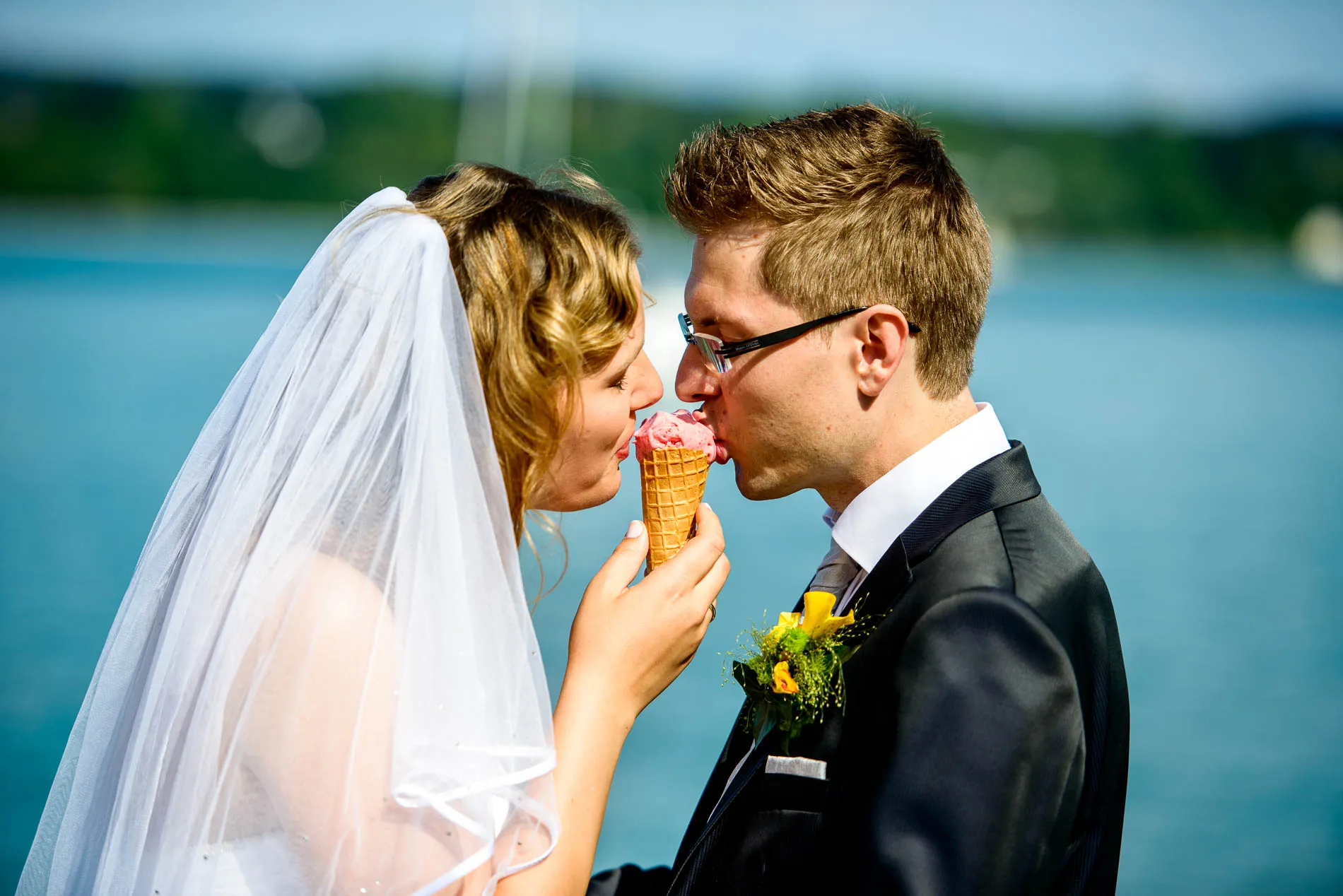 Brautpaar teilt Eis an ihrer Hochzeit am Starnberger See. Romantische Hochzeitsfotografie unter freiem Himmel.