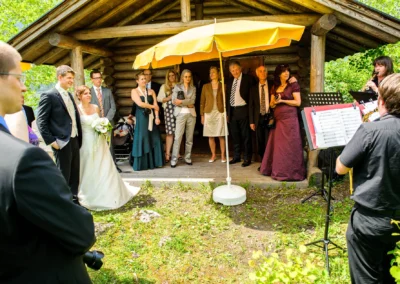 Brautpaar und Gaeste bei einer Hochzeitsfeier am Eibsee, begleitet von Musikern, aufgenommen von einem Hochzeitsfotografen.