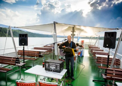 Gitarrist bei einer Hochzeit auf Schifffahrt Staffelsee, fröhliche Stimmung auf einem Schiff mit Blick auf den See.