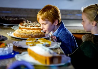 Junge und Maedchen bei einer Hochzeitsreportage nahe Tegernsee bewundern Kuchen. Hochzeitsfotografie in Aktion.