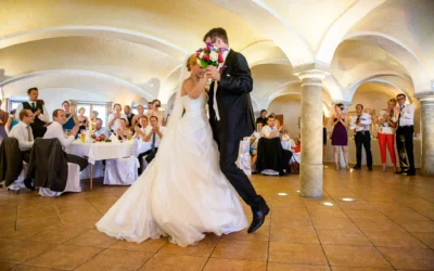 Brautpaar tanzt bei Hochzeitsreportage in Gewoelbe nahe Rosenheim, Gaeste klatschen und feiern im Hintergrund.