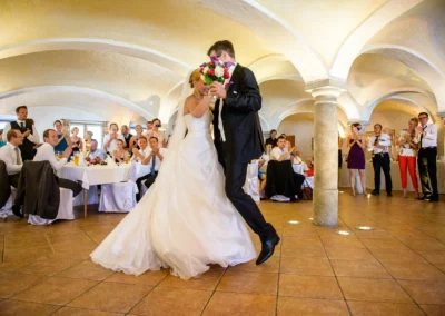 Brautpaar tanzt bei Hochzeitsreportage in Gewoelbe nahe Rosenheim, Gaeste klatschen und feiern im Hintergrund.