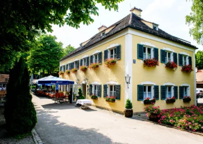 Gelbes Gebäude mit Blumendekor, Restaurantgarten in Moosach. Hochzeitsreportage-Aufnahme bei einer Hochzeit.