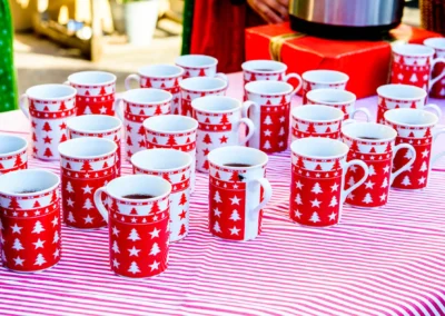 Rot-weiße Tassen mit Weihnachtsmuster auf gestreiftem Tischtuch bei Hochzeit in Bruckmühl. Hochzeitsreportage.