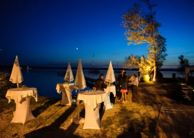 Abendstimmung bei einer Hochzeit am Starnbergersee. Stehtische und Hochzeitsgaeste unter einem klaren Nachthimmel.