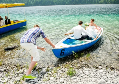 Brautpaar in Boot am Eibsee, Hochzeitsfotografie, Aufnahme bei Hochzeit im Wasser, Grainau im Hintergrund.