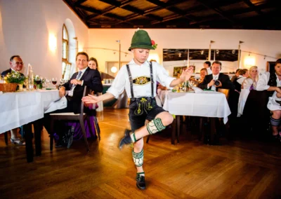 Junge tanzt auf einer Hochzeit in traditioneller Tracht im Kloster Seeon, Bayern. Hochzeitsreportage mit Gaesten.