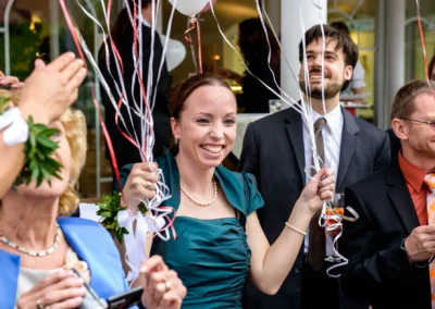 Hochzeitsfeier in Gmund mit lachenden Gaesten, die bunte Ballons halten. Hochzeitsfoto zeigt Freude und Gemeinschaft.