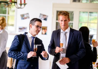 Zwei Männer im Anzug mit Sektgläsern bei Hochzeit im Hotel Kaiserin Elisabeth. Hochzeitsfoto in Feldafing.