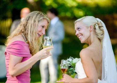 Braut in weissem Kleid und Frau im rosa Kleid bei Hochzeit am Starnberger See. Hochzeitsfotograf bei Schlossgut Oberambach.
