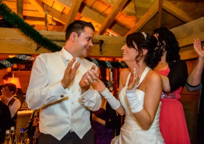 Brautpaar lacht und klatscht auf ihrer Hochzeit in Karlsfeld, festgehalten von einem Hochzeitsfotografen.