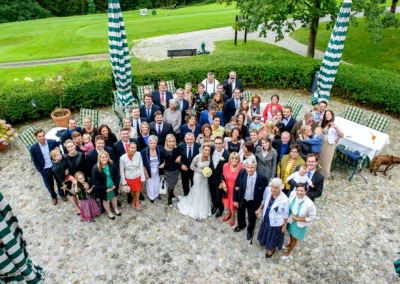 Gruppenfoto bei Hochzeit im Margarethenhof, Gaeste versammelt auf Terrasse mit Brautpaar im Zentrum, Hochzeitsfotografie.