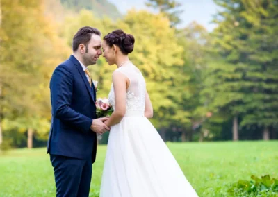 Brautpaar bei Hochzeitsfoto im Gruenen nahe Schliersee, Bergkulisse im Hintergrund, Hochzeitsfotograf aus Muenchen.