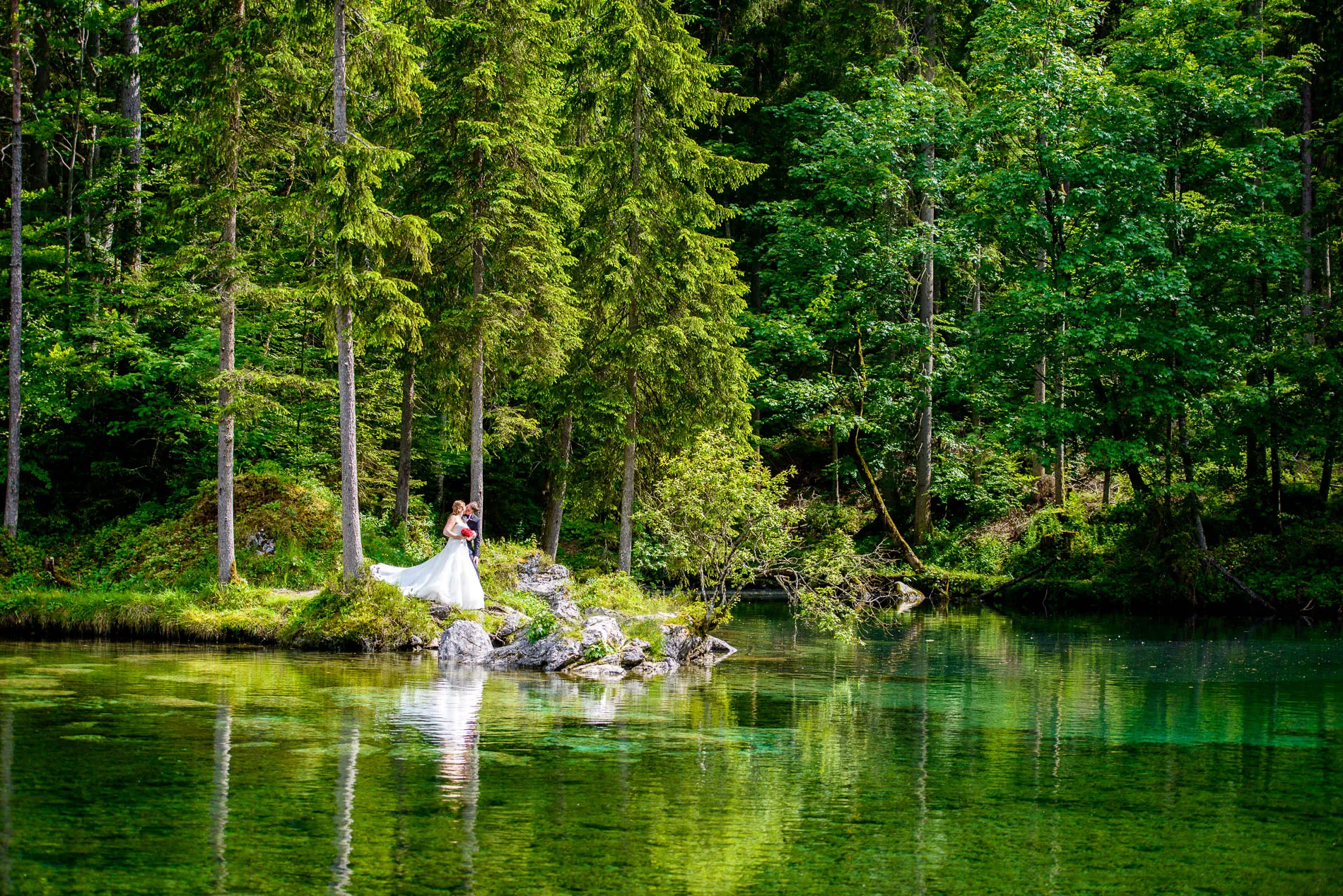 Brautpaar bei Hochzeit im Wald am Badersee, umgeben von grünen Bäumen, festgehalten in einem Hochzeitsfoto.