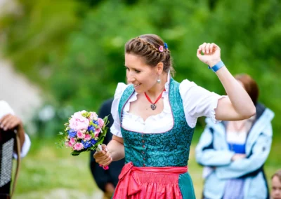 Frau im traditionellen Kleid mit Blumenstrauss bei Hochzeit in Oberbayern, aufgenommen von Hochzeitsfotograf.