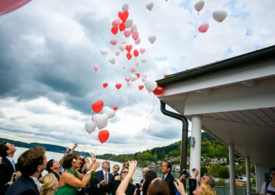 Gäste lassen Herzballons bei einer Hochzeit am Tegernsee steigen, festgehalten von einem Hochzeitsfotografen.