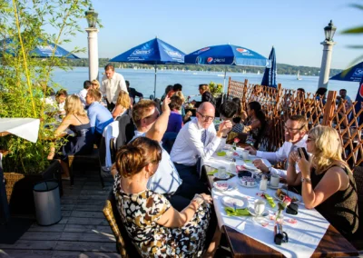 Hochzeitsgesellschaf feiert bei Sonnenlicht, Hugos Beach Club am Starnberger See, entspannte Hochzeitsreportage.