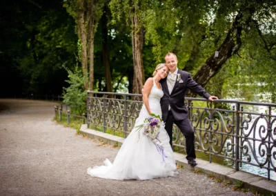 Brautpaar bei Hochzeitsportraits am Seehaus im Englischen Garten, lehnt an Bruecke, Hochzeitsfotografie in Muenchen.