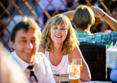 Gäste bei einer Hochzeitsfeier am Starnberger See genießen die Feierlichkeiten und lächeln in geselliger Runde.