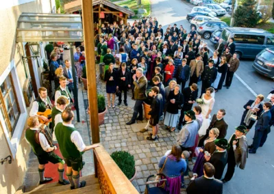 Hochzeitsempfang beim Hofgut zur Muehle mit Gaesten in traditioneller Tracht und Brautpaar in eleganter Kleidung.