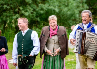 Lachende Hochzeitsgesellschaft in traditioneller Tracht bei der Hochzeit in Almbad-Sillberghaus. Hochzeitsreportage.