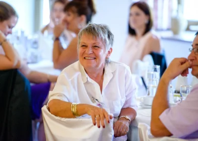 Geselliges Beisammensein bei einer Hochzeitsfeier südlich München mit lächelnder Dame im Vordergrund.