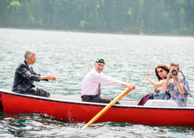 Menschen in einem roten Boot auf dem Eibsee bei einer Hochzeitsreportage, lachen und fotografieren die Umgebung.