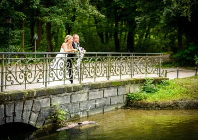 Brautpaar auf Brücke im Englischen Garten, München. Hochzeitsportraits im Grünen mit romantischem Hintergrund.