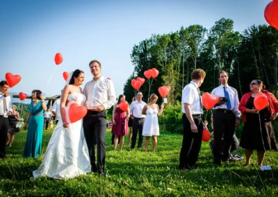 Brautpaar mit roten Herzballons auf Wiese bei Hochzeitsfeier in Oberbayern, Hochzeitsfotografie.