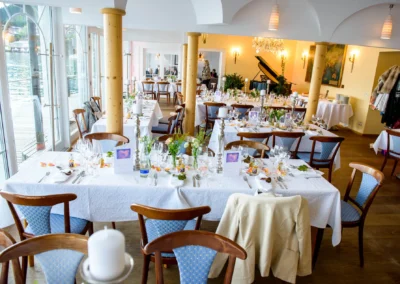 Elegant gedeckte Tische in einem Hochzeitslocation am Tegernsee mit Klavier im Hintergrund. Hochzeitsfotografie.
