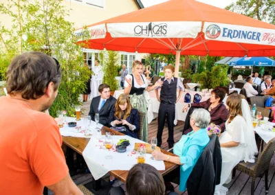 Hochzeitsreportage in Hugos Beach Club: Gäste unterhalten sich unter einem großen Sonnenschirm.