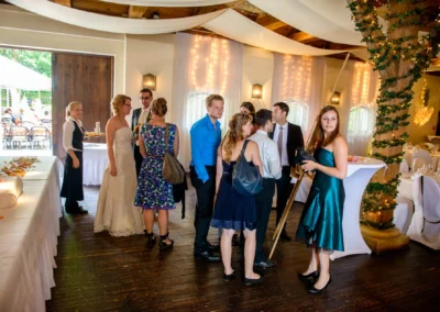Gaste bei einer Hochzeit in Moosach, Austausch im festlich geschmuckten Saal, Hochzeitsfotografie von einem Fotografen.