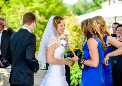 Braut im weissen Kleid lacht mit Gaesten bei Hochzeit im Hotel Vier Jahreszeiten Starnberg. Hochzeitsreportage.