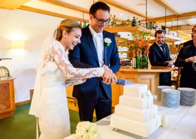 Brautpaar schneidet Hochzeitstorte bei Hochzeitsfeier in Waakirchen nahe Tegernsee, festgehalten von Hochzeitsfotograf.