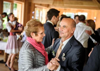 Älteres Paar tanzt auf Hochzeit in Sauerlach, umgeben von feiernden Gaesten. Hochzeitsfotografie im Landhotel Schmuck.