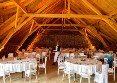 Runder Hochzeitstisch mit weißer Tischdecke unter Holzdach in Gut Thurnsberg, Oberbayern, bei einer Hochzeit.