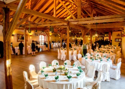 Rustikaler Hochzeitsempfang in einer Scheune bei Hofgut zur Muehle, festlich gedeckte Tische und Gaeste.