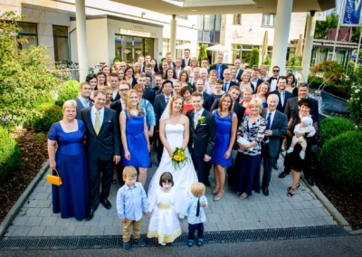 Hochzeitsgesellschaft vor Hotel Vier Jahreszeiten Starnberg, Brautpaar umgeben von Gaesten bei der Hochzeitsreportage.