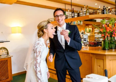 Brautpaar bei Hochzeitsreportage lacht und nascht im Margarethenhof. Hochzeit nahe Tegernsee.